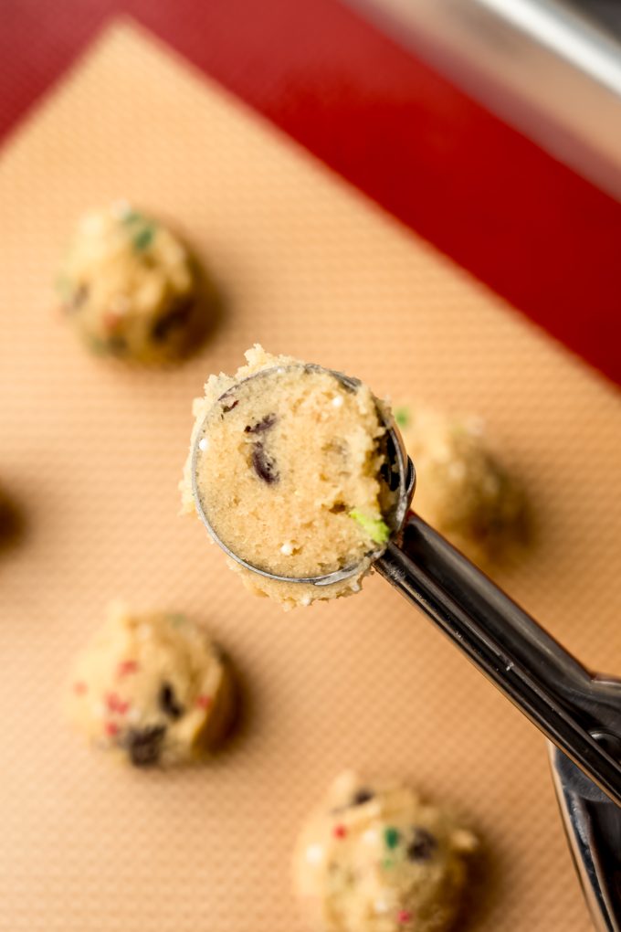 A mini cookie scoop filled with Christmas chocolate chip cookie dough.