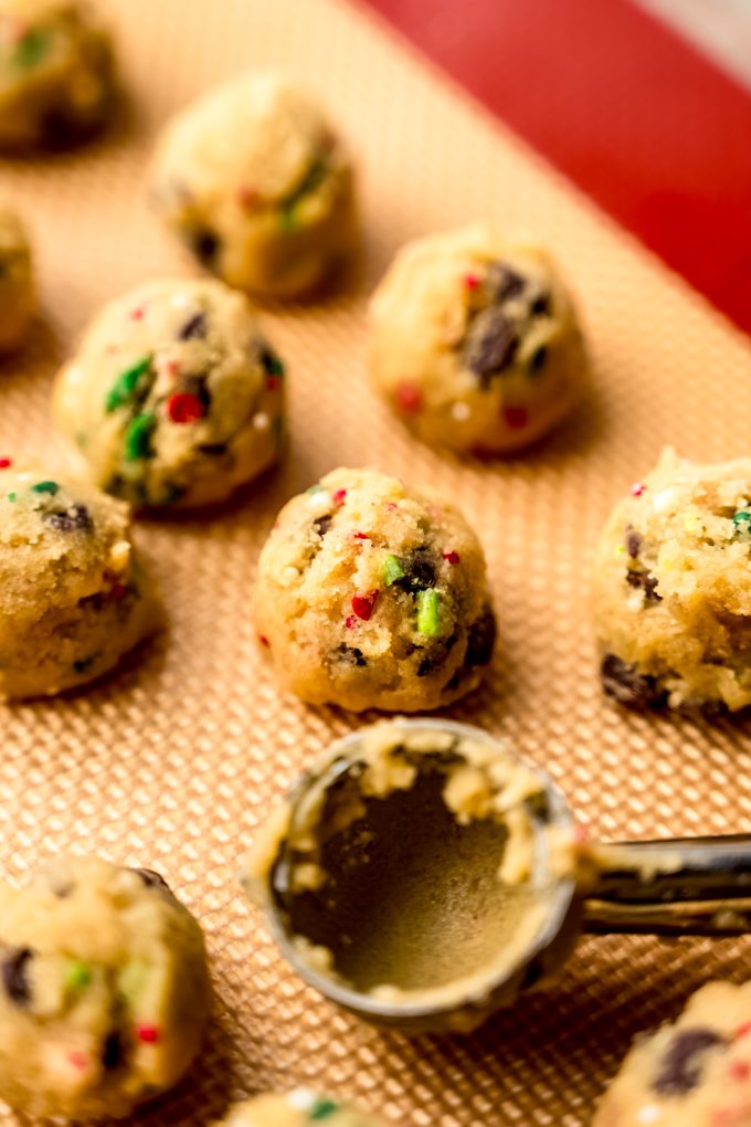 Mini Christmas chocolate chip cookie dough balls sitting on a baking sheet.