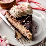 A slice of peppermint bark cheesecake on a plate with a fork.