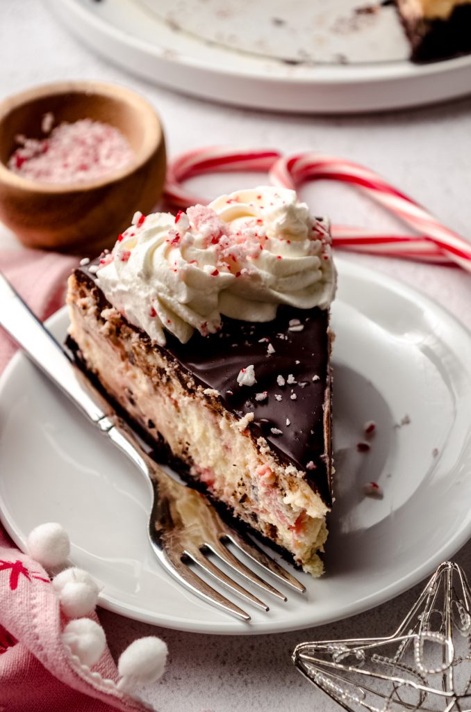 A slice of peppermint bark cheesecake on a plate with a fork.