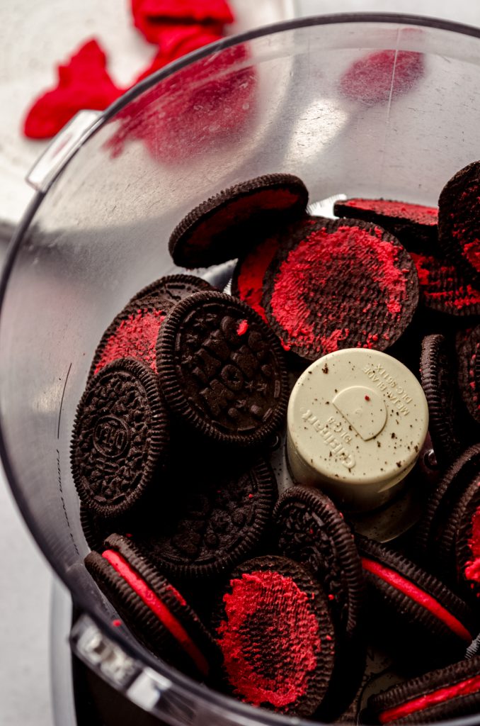 The drum of a food processor with holiday Oreos in it and some of the Oreos have had the filling removed.