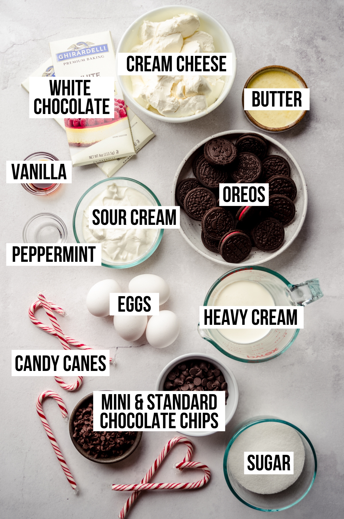 Aerial photo of ingredients to make peppermint bark cheesecake with text overlay labeling each ingredient.