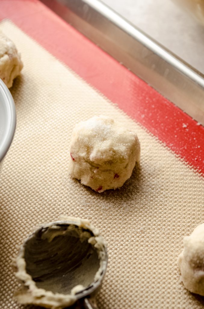 A ball of white chocolate peppermint cookie dough on a baking sheet.