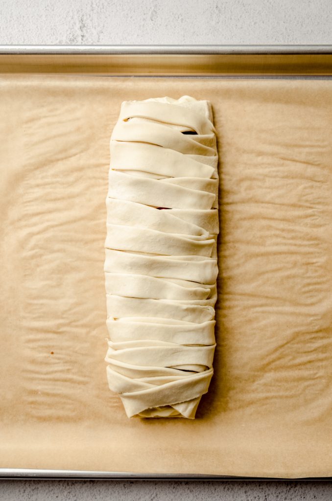 A braided pastry on a baking sheet lined with parchment paper.