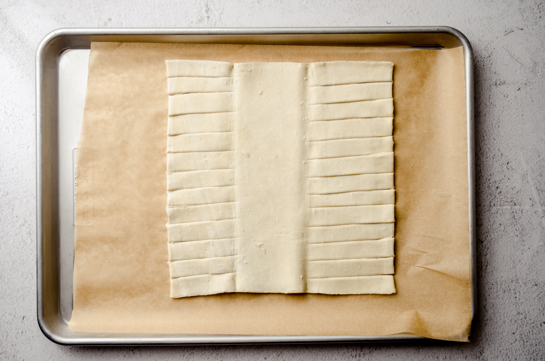 A rectangle of puff pastry dough on a baking sheet lined with parchment paper.