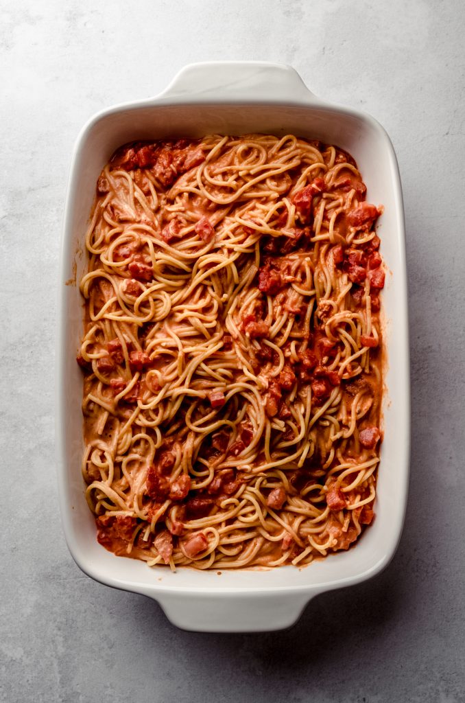 Aerial photo of spaghetti with sauce and tomatoes in a baking dish ready to make spaghetti casserole.