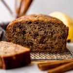 A photo of a loaf of banana bread made with unripe bananas on a cooling rack.