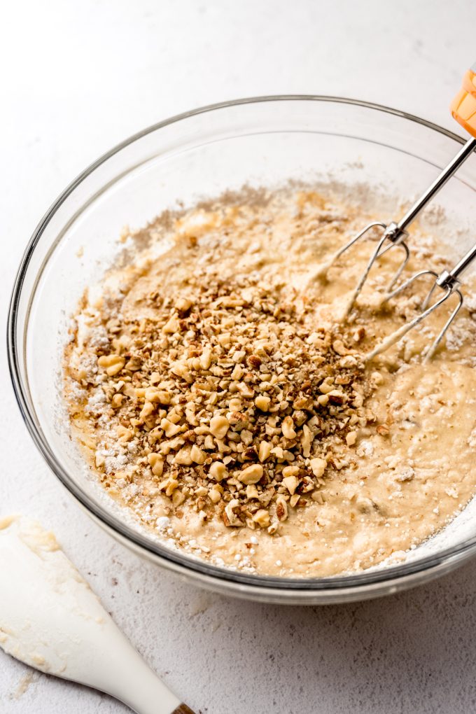 Banana bread batter in a bowl with electric beaters before the chopped nuts have been stirred in.