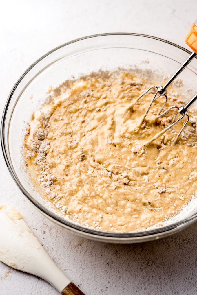 Banana bread batter in a bowl with electric beaters.