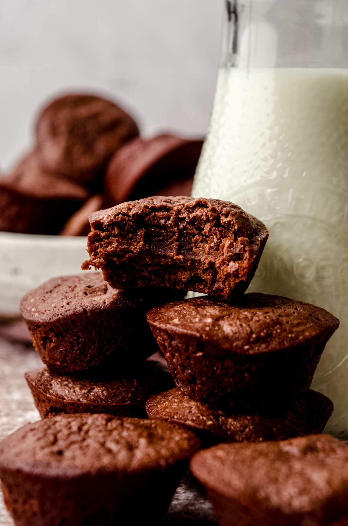 A stack of brownie bites with a bottle of milk in the background.