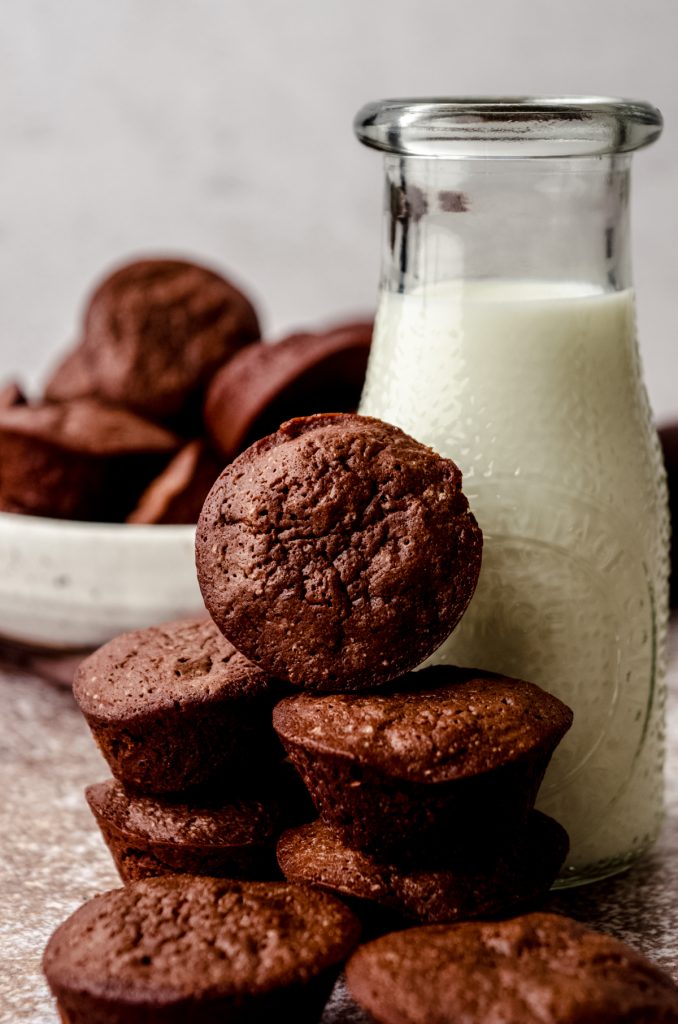 A stack of brownie bites with a bottle of milk in the background.