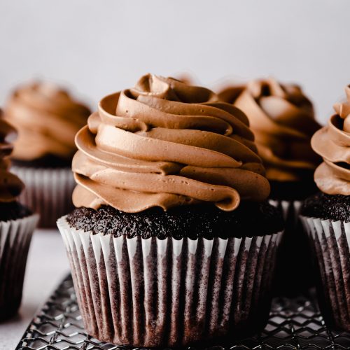 Chocolate cupcakes with chocolate Swiss meringue buttercream piped on top.