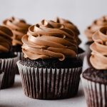 Chocolate cupcakes with chocolate Swiss meringue buttercream piped on top.