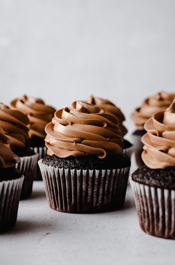 Chocolate cupcakes with chocolate Swiss meringue buttercream piped on top.