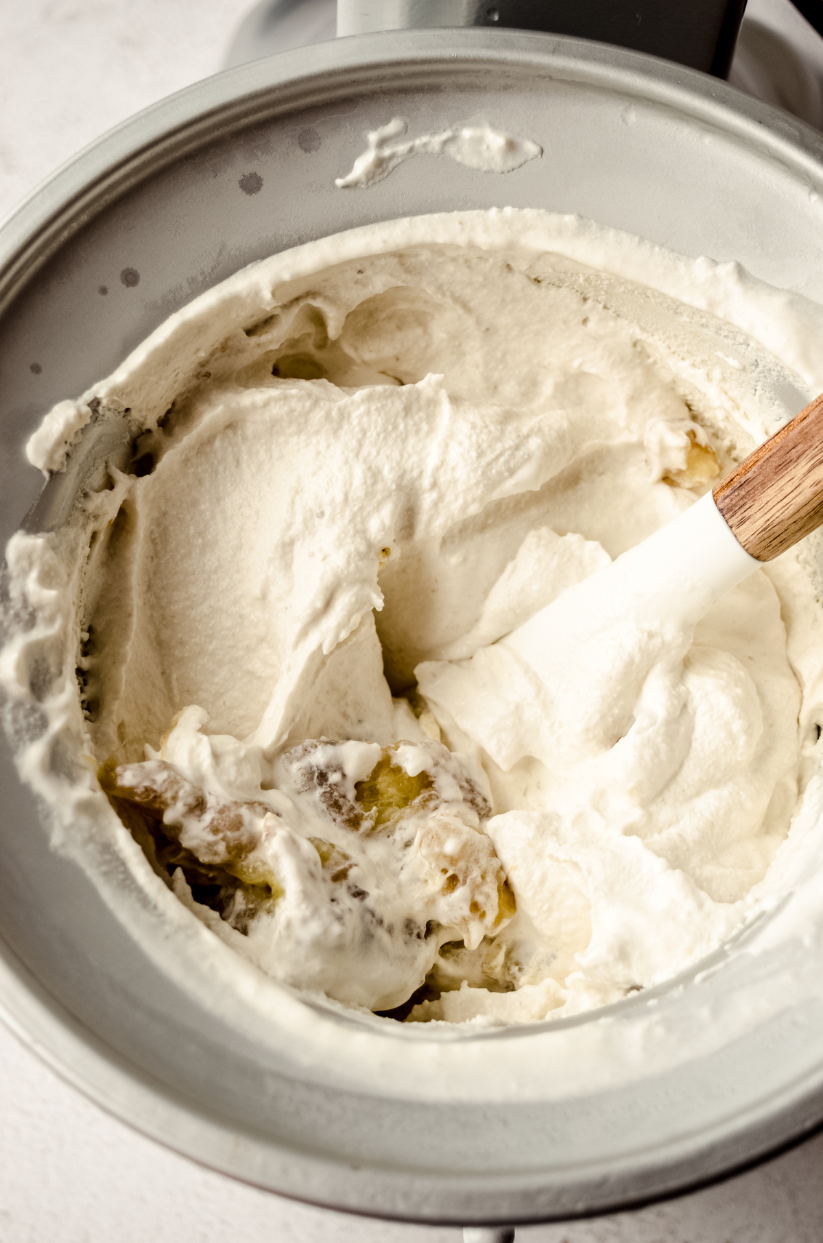 An ice cream maker filled with homemade ice cream and roasted mashed bananas stirred into it.