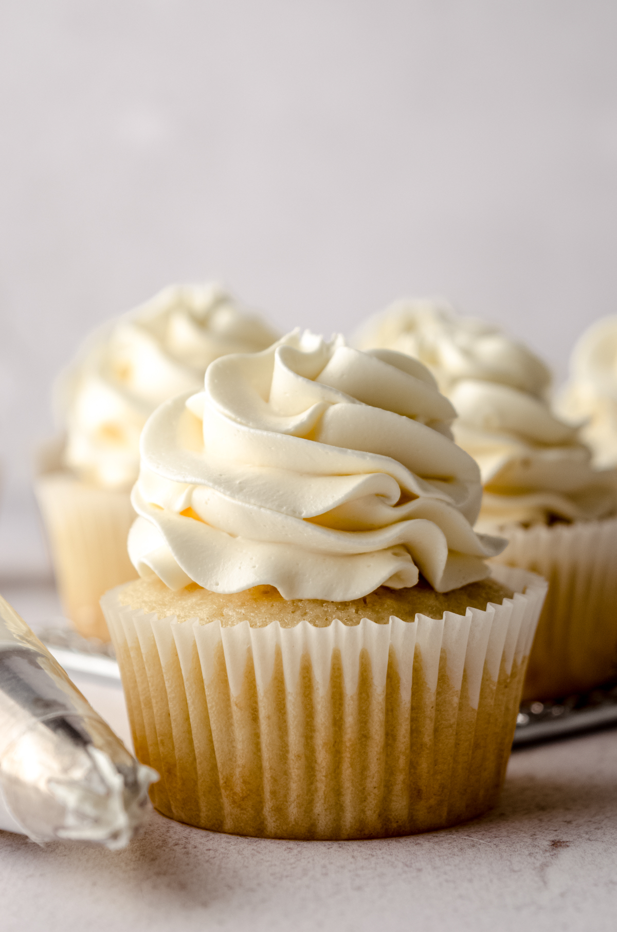 Vanilla cupcakes with a swirl of Swiss meringue buttercream piped on top.