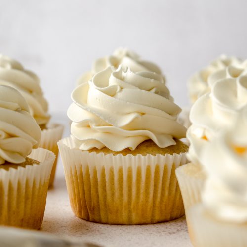 Vanilla cupcakes with a swirl of Swiss meringue buttercream piped on top.