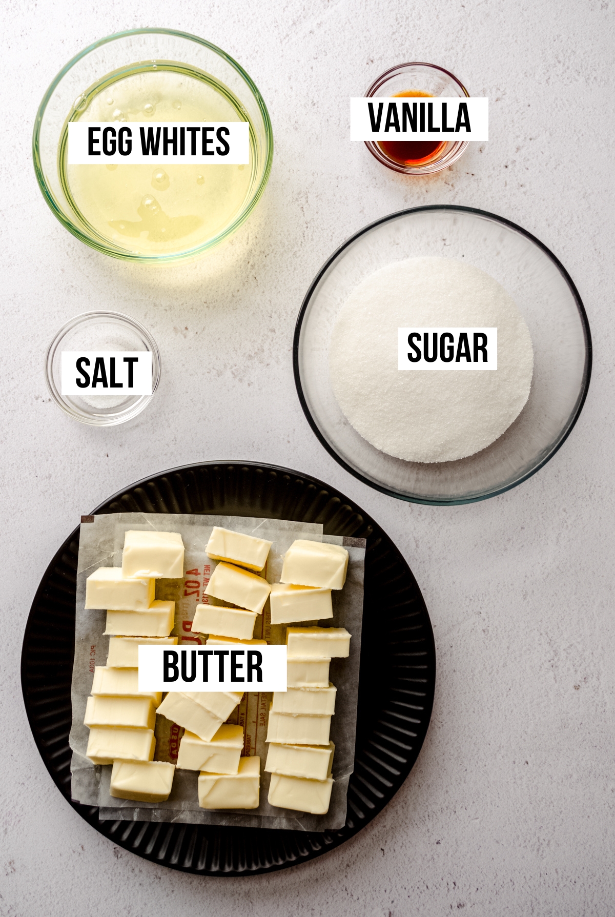 Aerial photo of ingredients to make Swiss meringue buttercream with text overlay labeling each ingredient. 