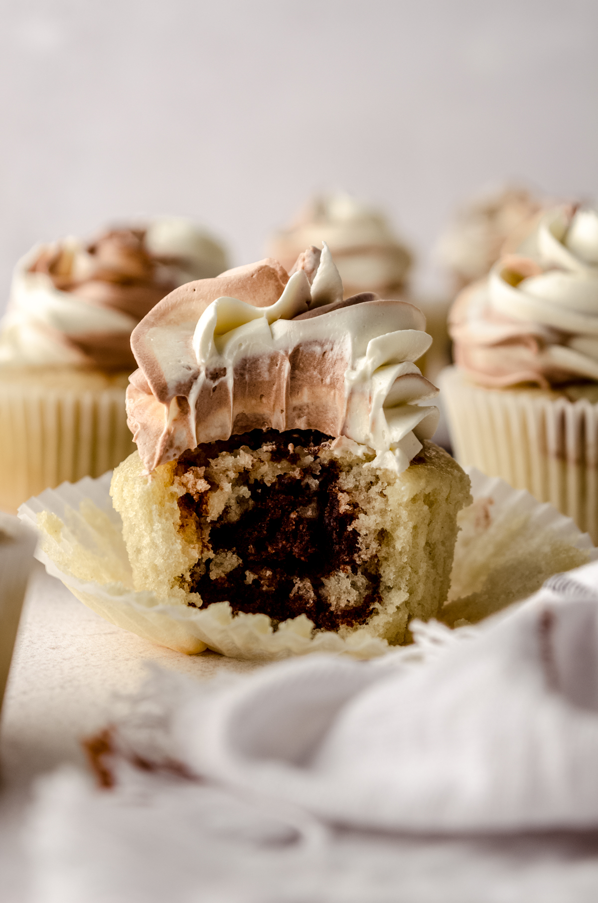 A marble cupcake with a bite taken out of it so you can see the inside of it.