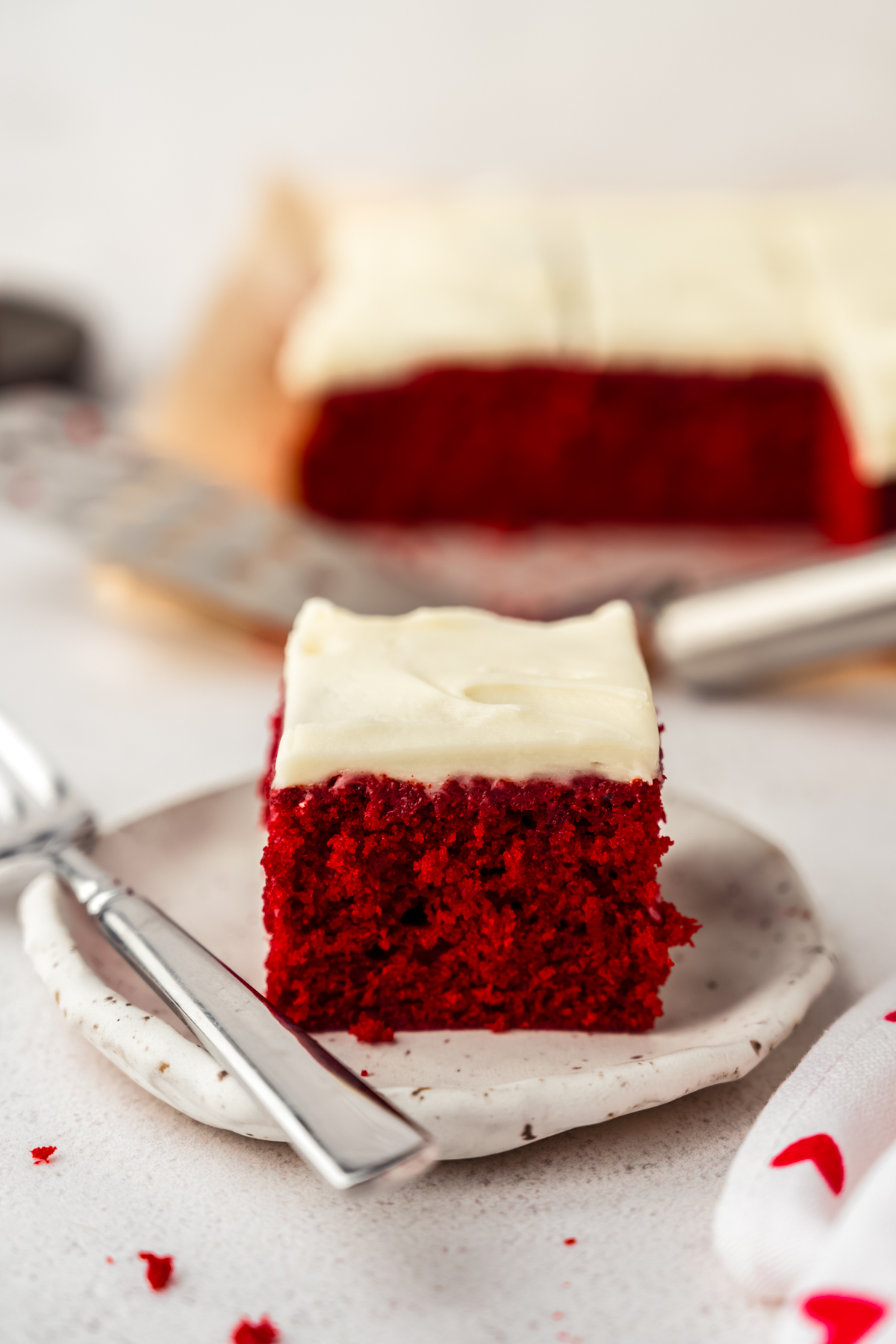 A slice of red velvet sheet cake on a plate with a fork.