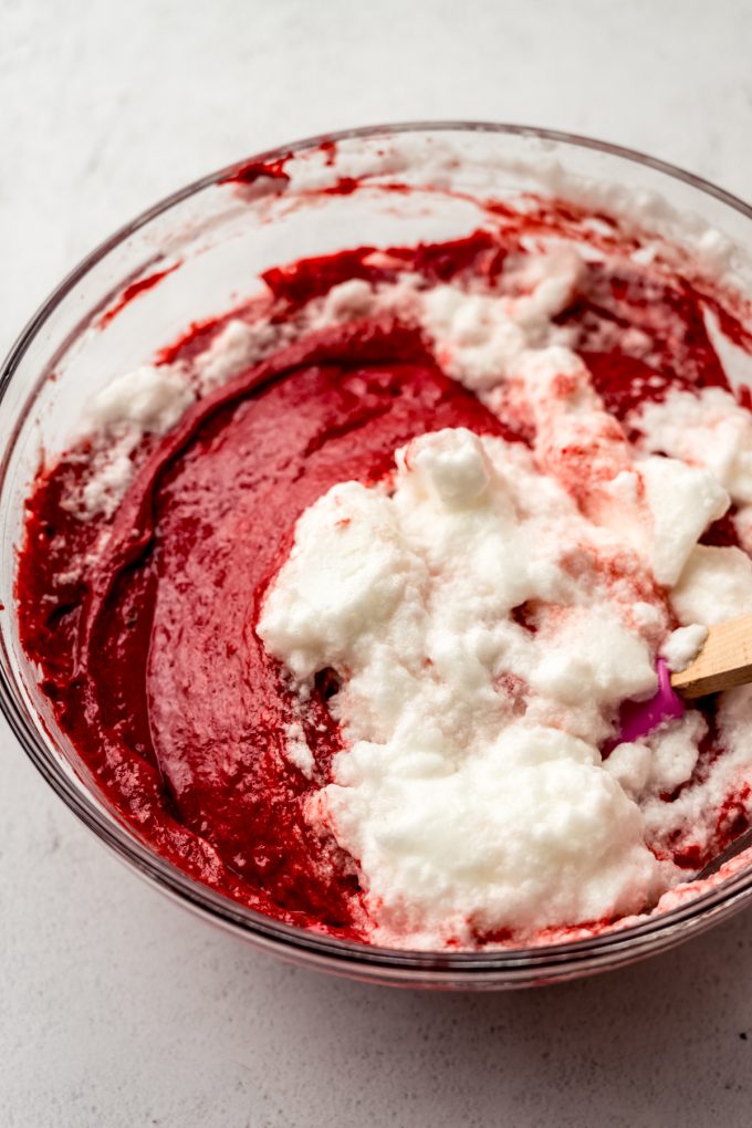 A bowl of red velvet sheet cake batter after whipped egg whites have started to be incorporated into it.