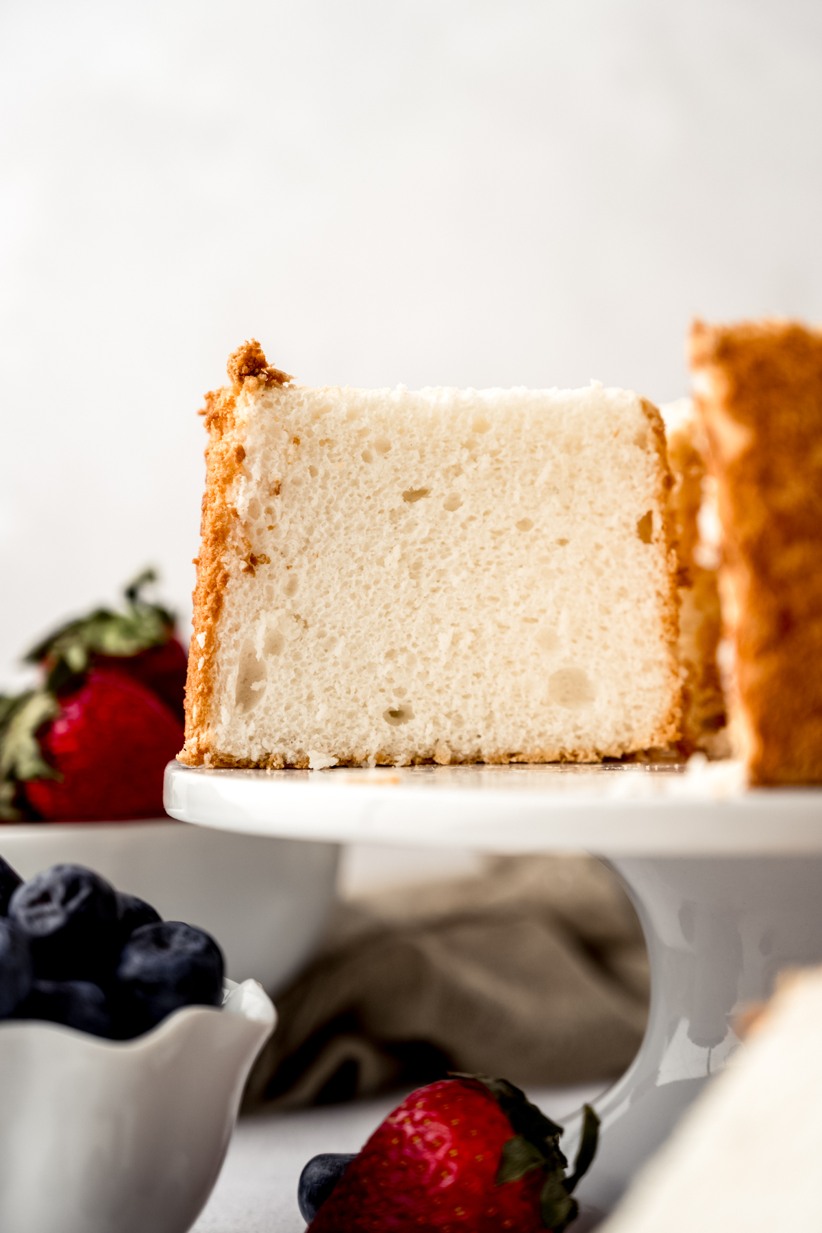 Angel food cake on a cake stand sliced so you can see the inside crumb.