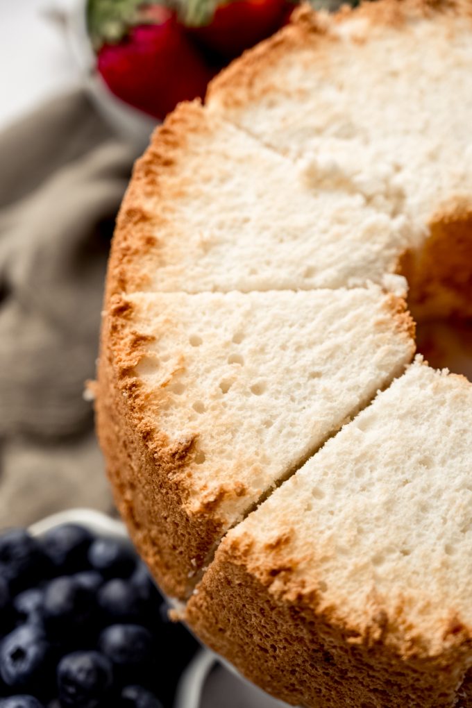 Angel food cake that has been sliced sitting on a cake stand.