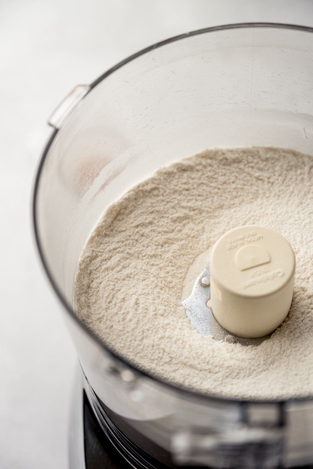 The drum of a food processor with dry ingredients in it.