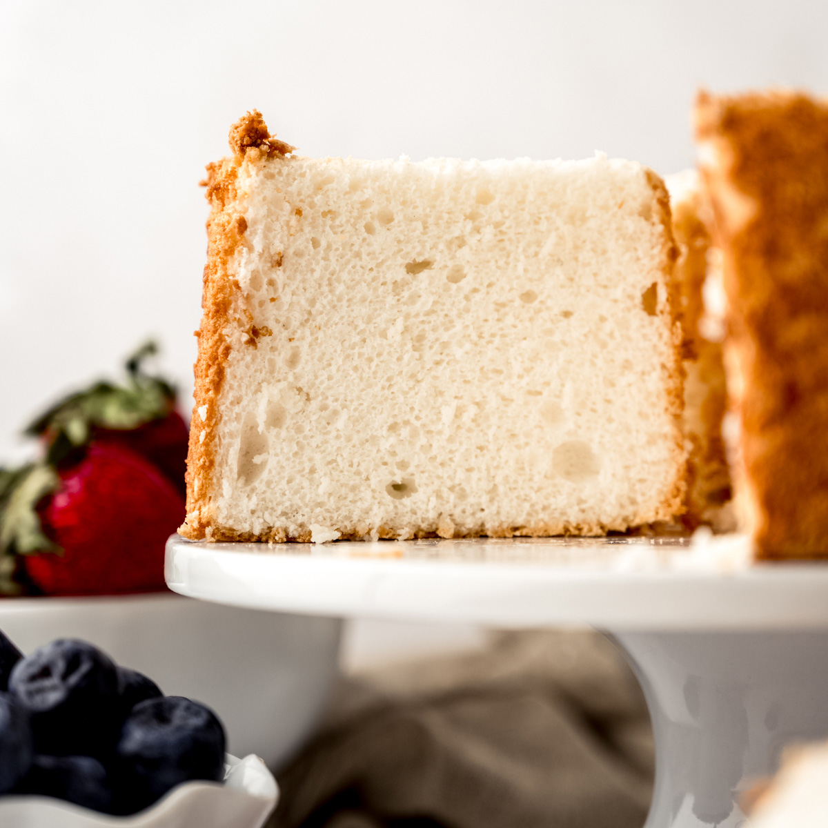 Angel food cake on a cake stand sliced so you can see the inside crumb.