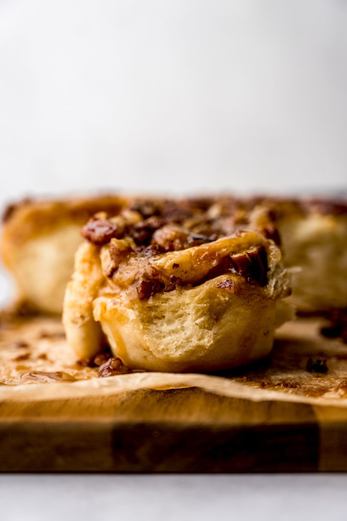 A sticky bun on a wooden platform lined with parchment paper.