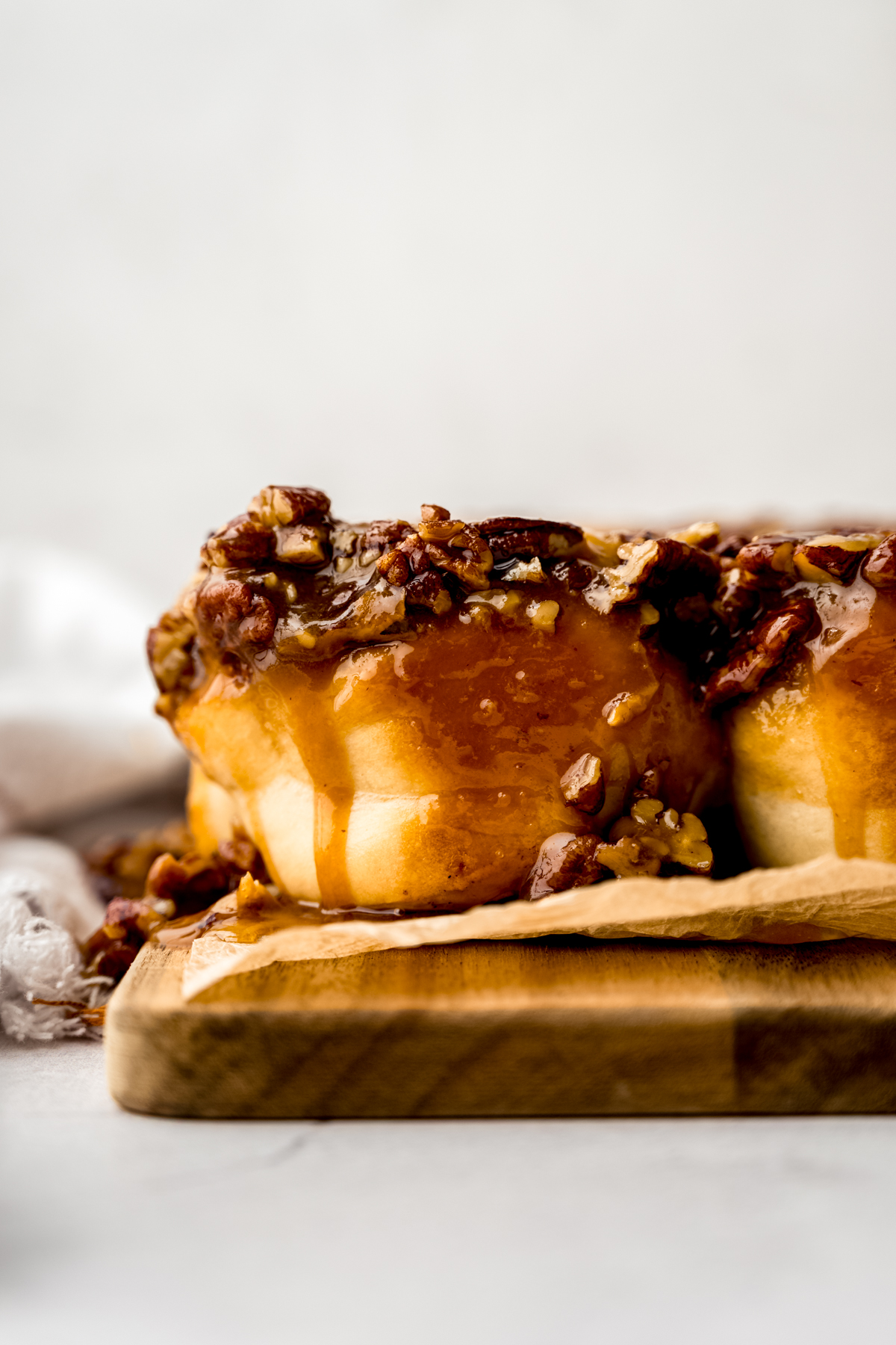 Sticky buns on a wooden platform lined with parchment paper.