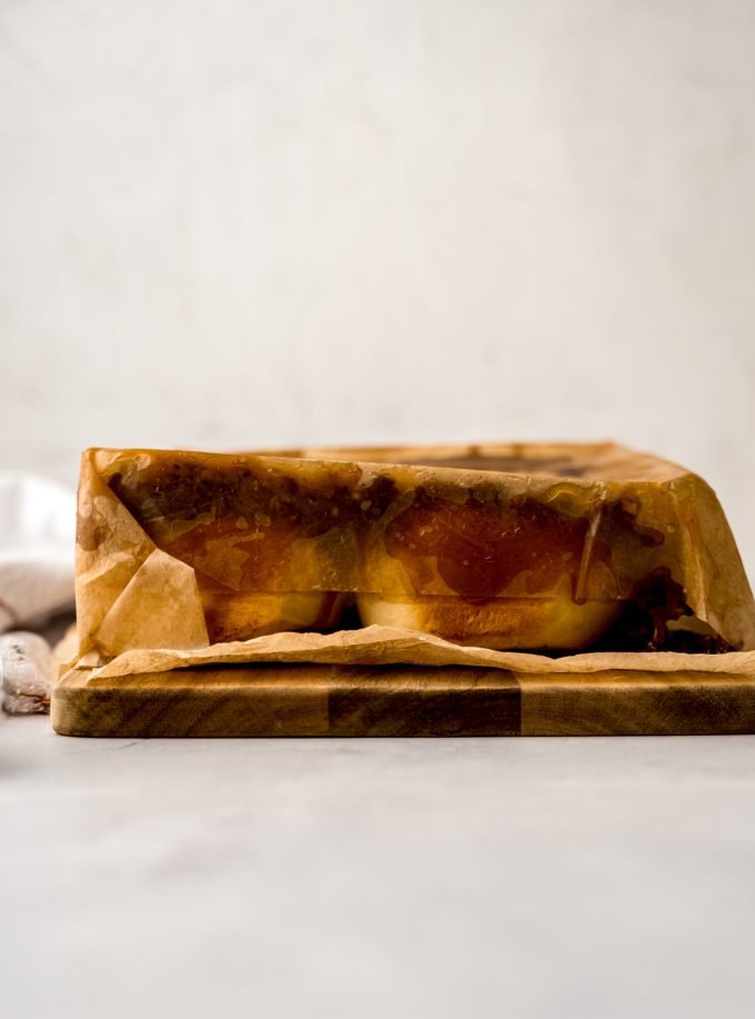 Sticky buns on a wooden platform lined with parchment paper with parchment paper on top ready to be peeled off.