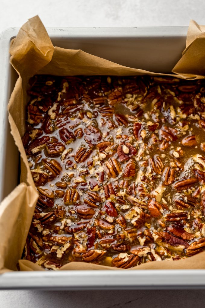 A pan lined with pecans and a maple caramel sauce to make sticky buns.