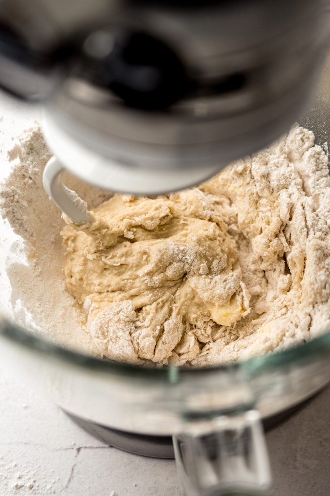 A yeast dough coming together in the bowl of a stand mixer with the hook attachment.