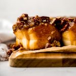 Sticky buns on a wooden platform lined with parchment paper.