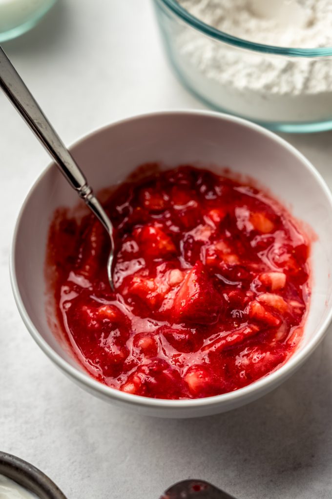 A bowl of pureed strawberries with a spoon in it.