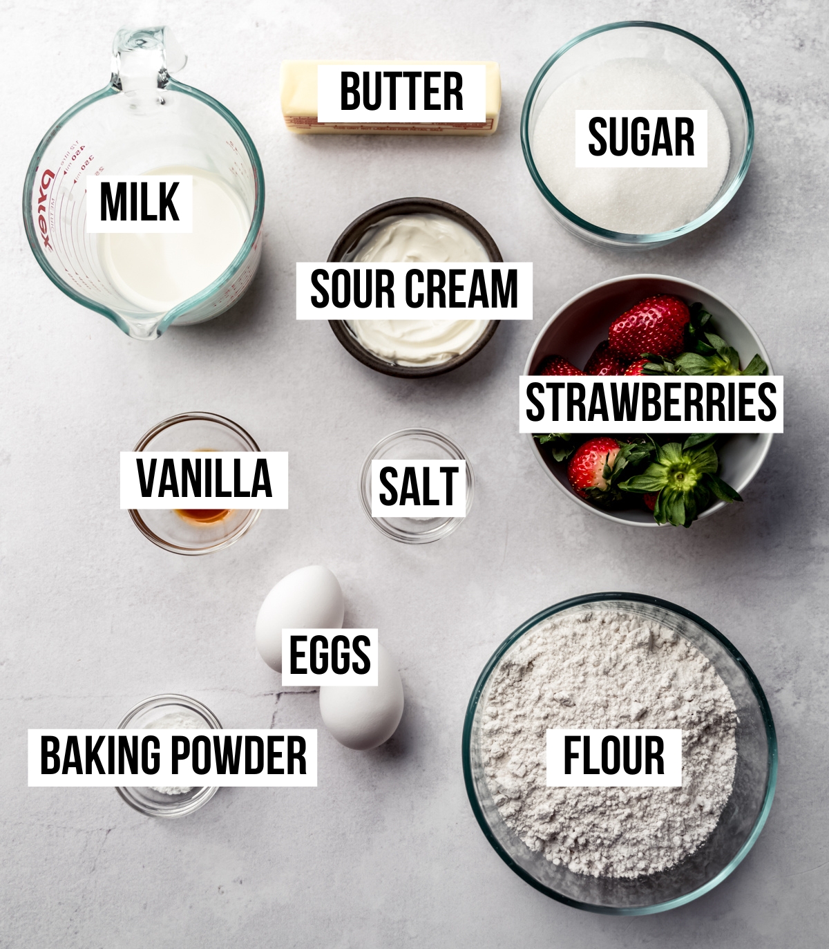 Aerial photo of ingredients to make strawberry cupcakes with text overlay labeling each ingredient.