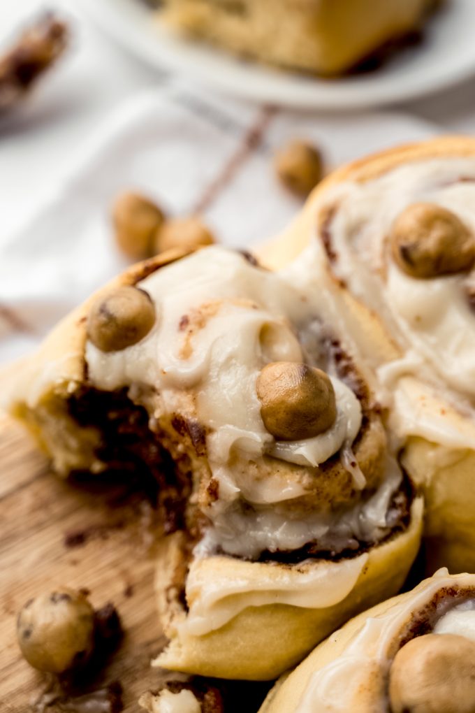 Cookie dough cinnamon rolls on a surface and one has a bite taken out of it.