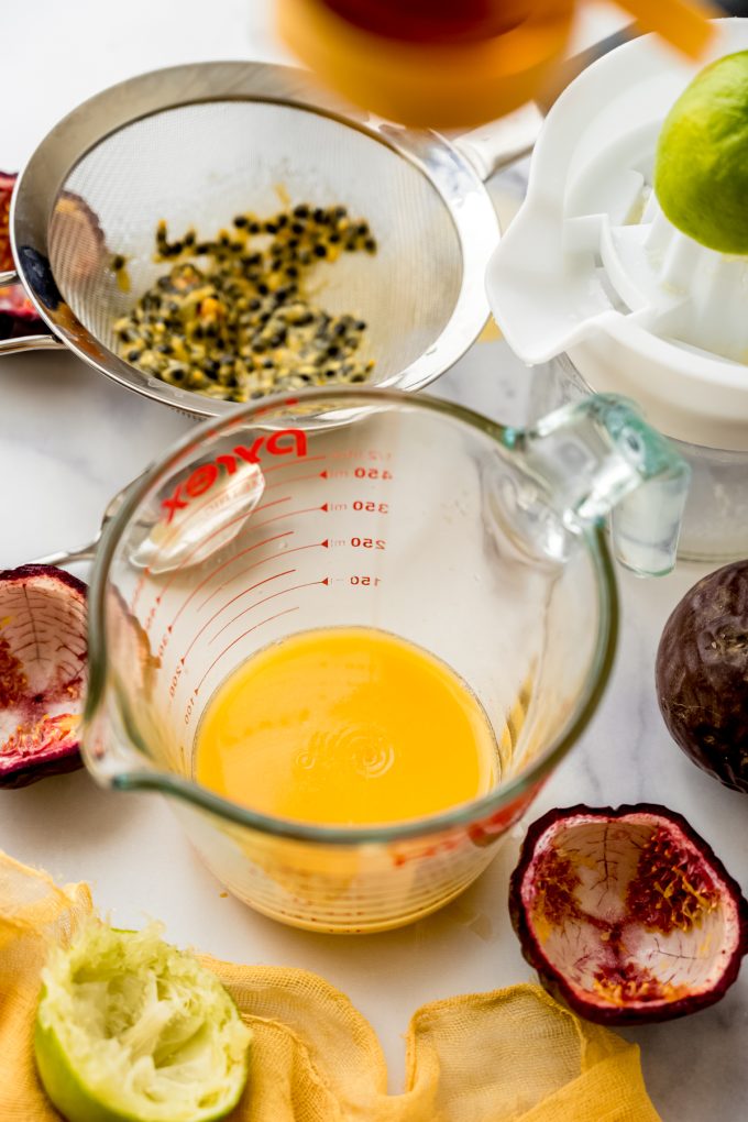 Passion fruit juice in a glass measuring cup that someone is squeezing honey into.
