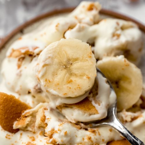 A photo of a spoon with a bite of banana pudding on it.