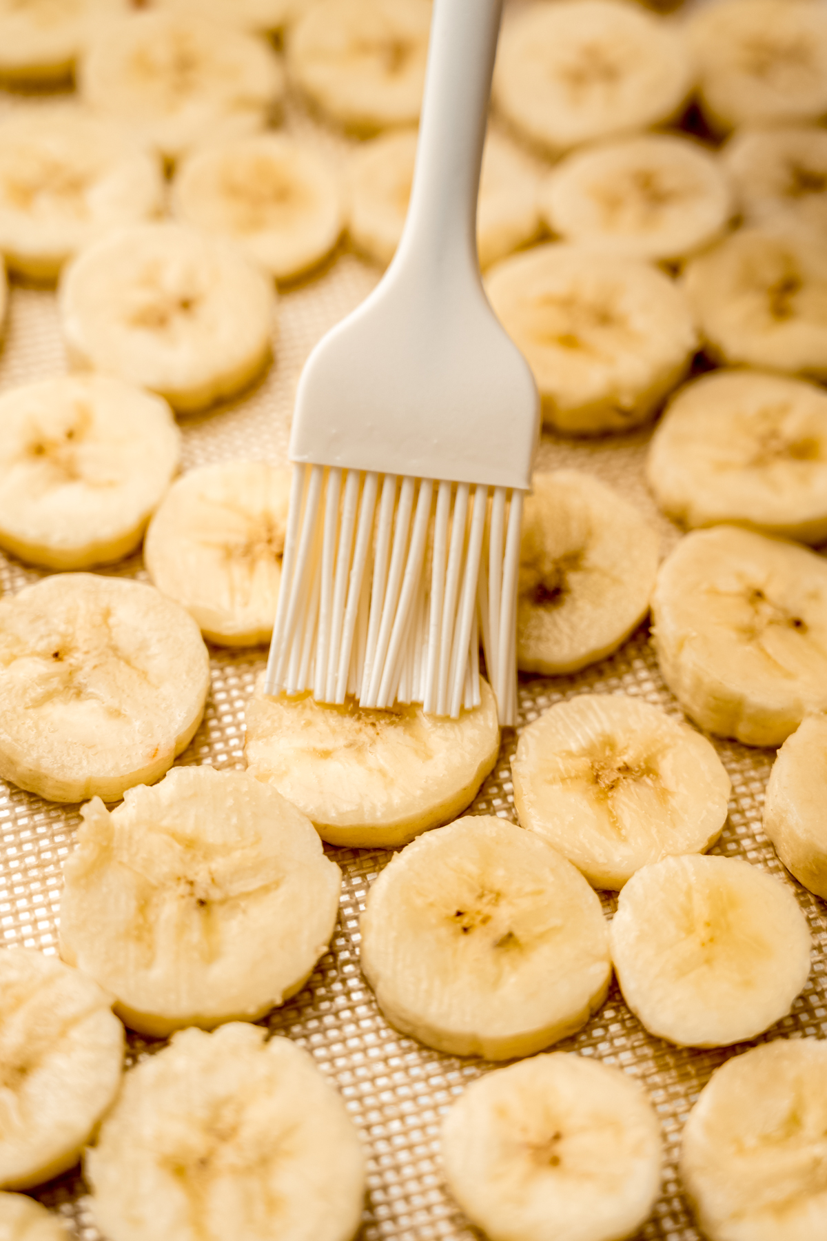 Someone is brushing banana slices with a pastry brush.