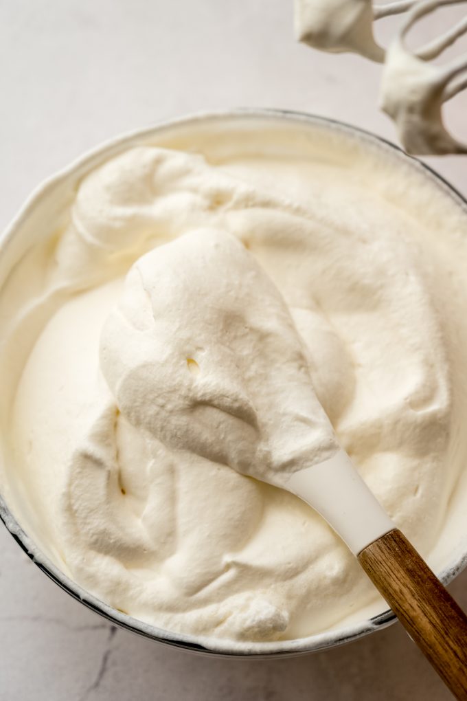 Aerial photo of a spatula scooping from a bowl of whipped cream.