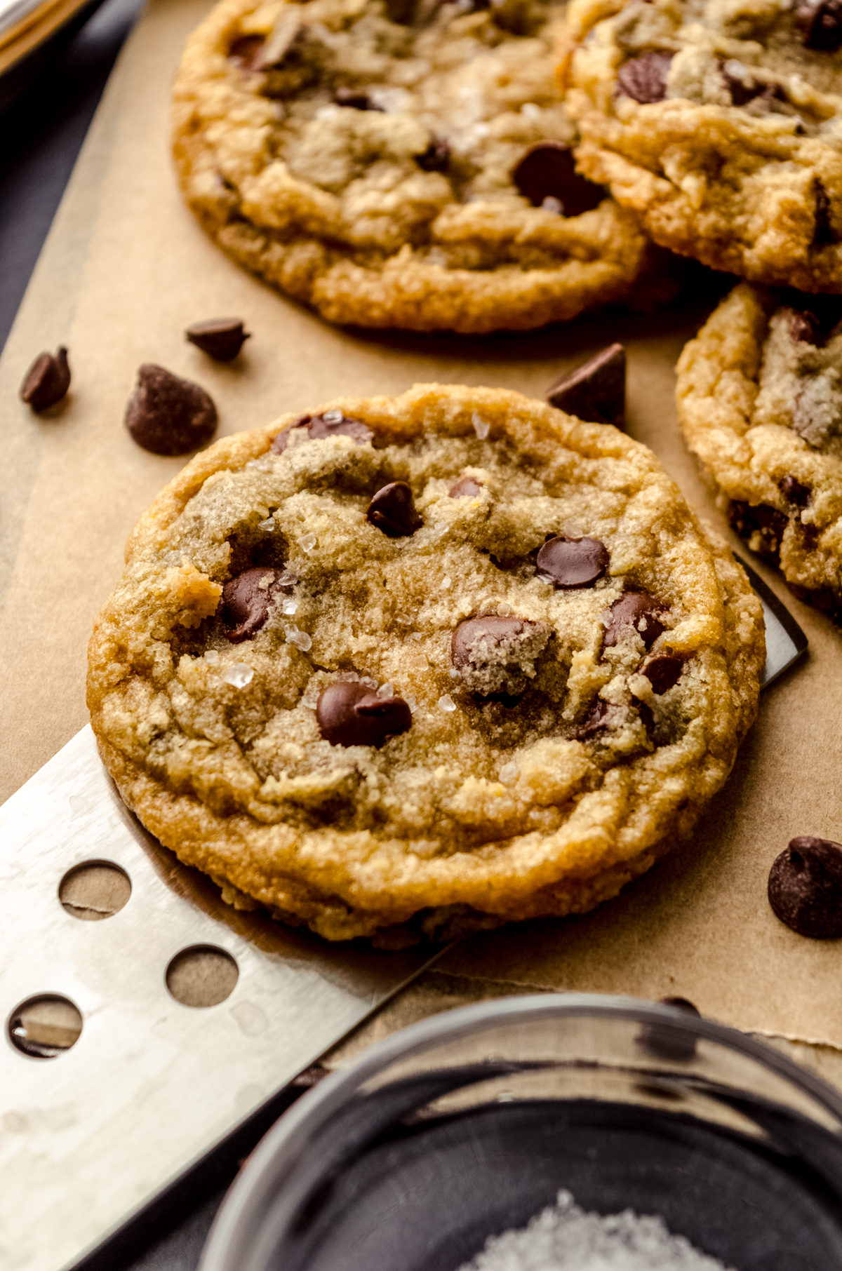 Someone is using a spatula to scoop a brown butter chocolate chip cookie off of a surface.