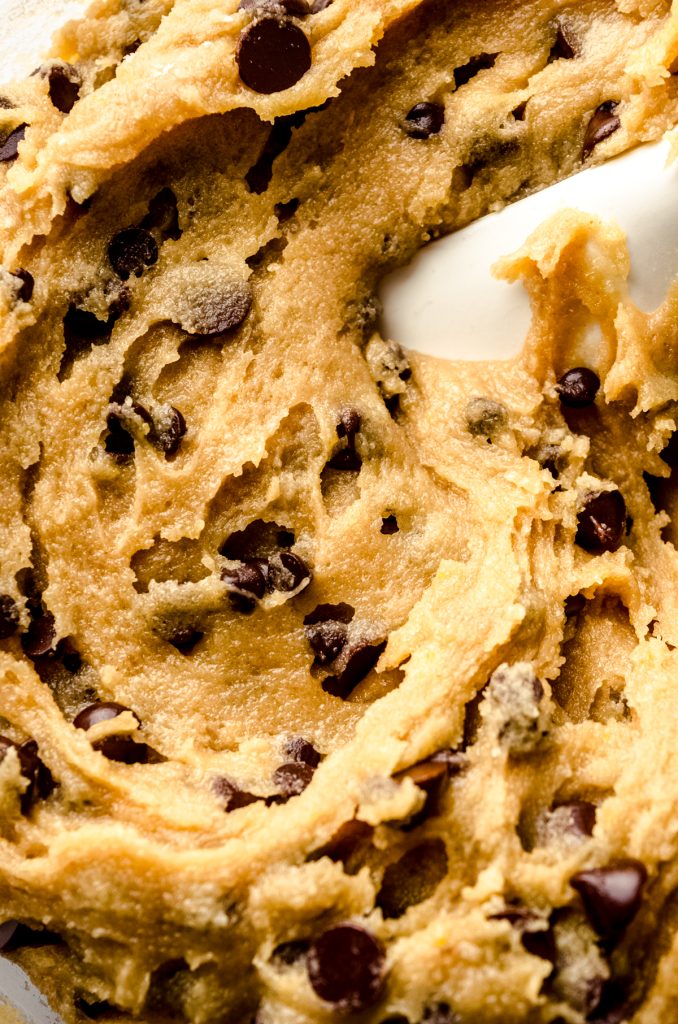 A closeup photo of brown butter chocolate chip cookie dough with a spatula in it.