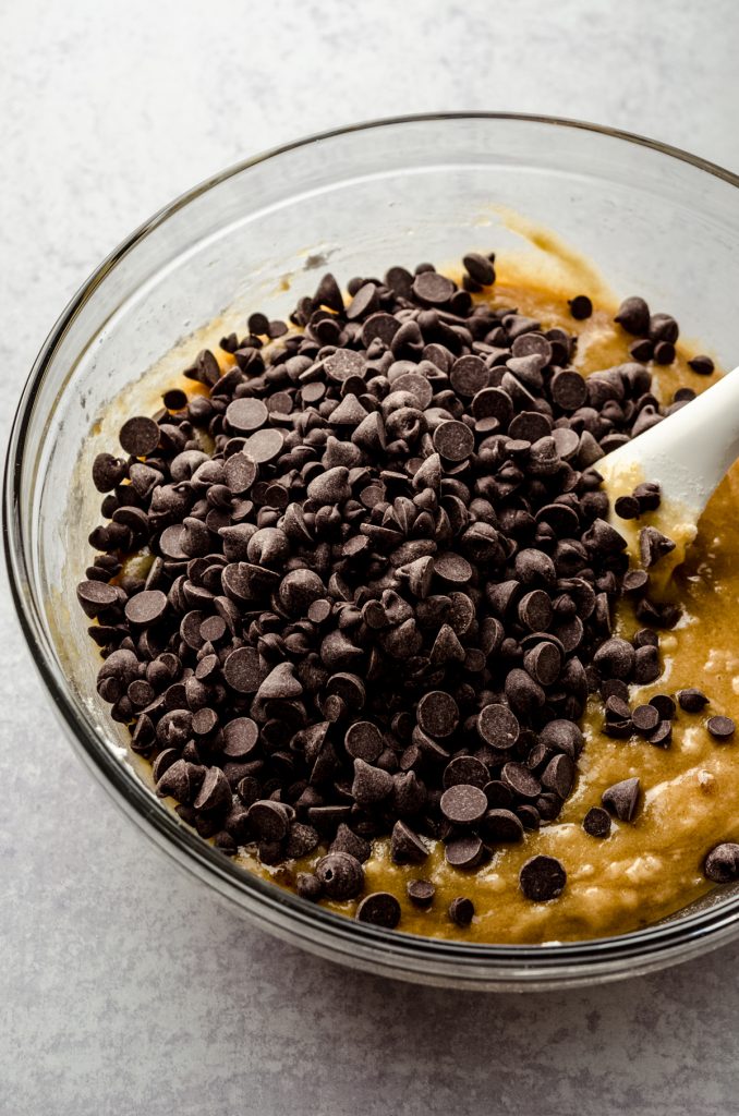 A bowl of ingredients to make brown butter chocolate chip cookies with a spatula in it.