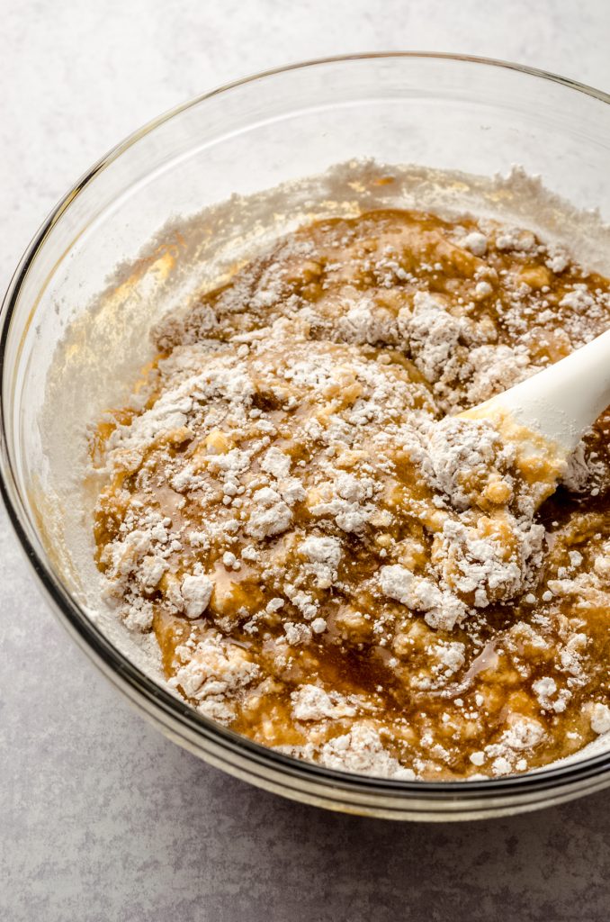 A bowl of ingredients to make brown butter chocolate chip cookies with a spatula in it.