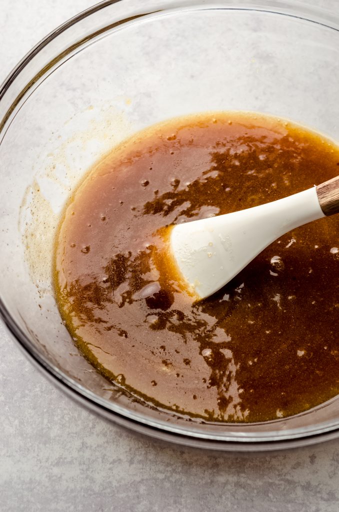 A bowl of ingredients to make brown butter chocolate chip cookies with a spatula in it.