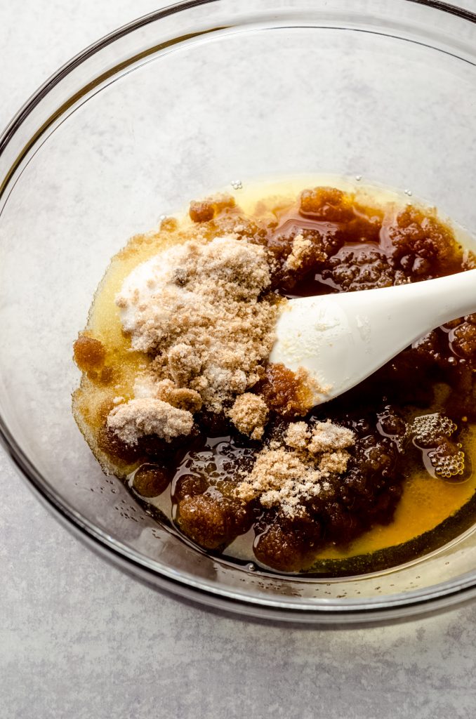 A bowl of ingredients to make brown butter chocolate chip cookies with a spatula in it.