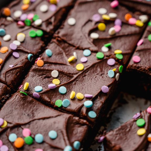 A chocolate sheet cake that has been sliced sitting in a baking pan.