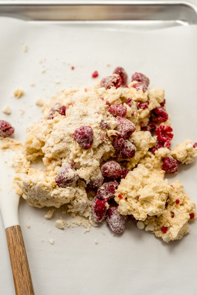 Raspberry white chocolate chip scone dough on a surface before getting pressed into a disc.